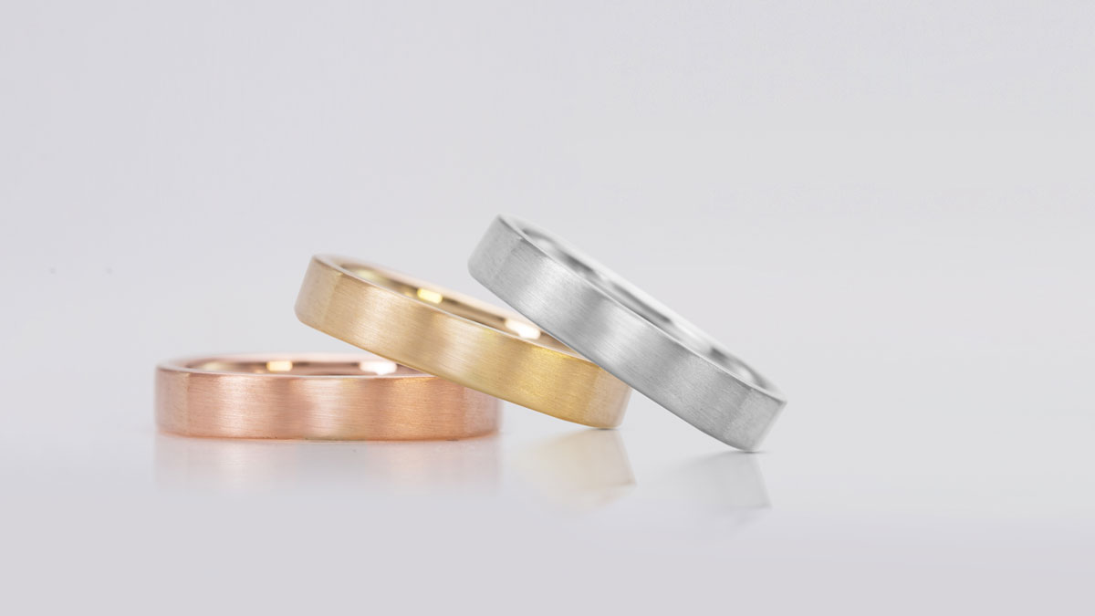 A stack of plain wedding rings in white gold, yellow gold and rose gold.