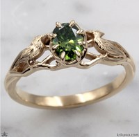 A gold ring featuring a green gemstone and intricate designs.